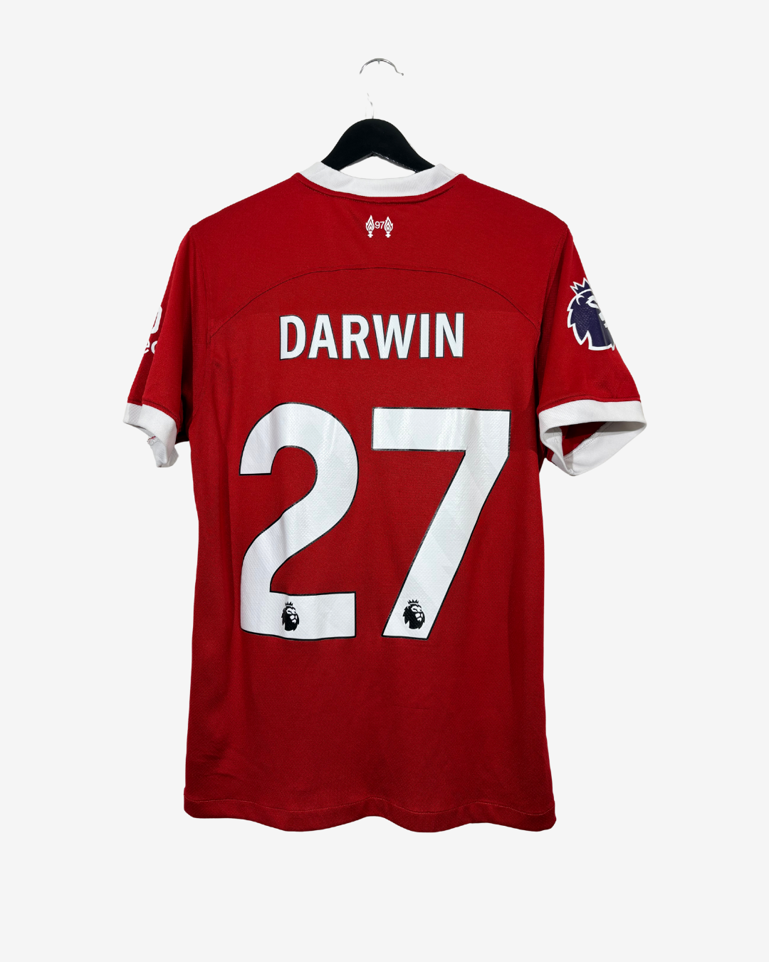 A red Nike  Darwin number 27 soccer jersey hanging on a black hanger against a light gray background.