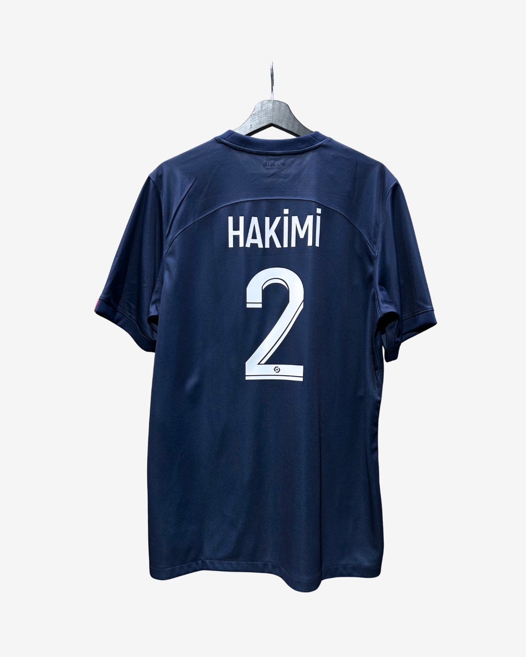 A navy blue short-sleeve soccer jersey hanging on a gray hanger against a light gray background. The back of the jersey features the name 'HAKIMI' and the number '2' in white.
