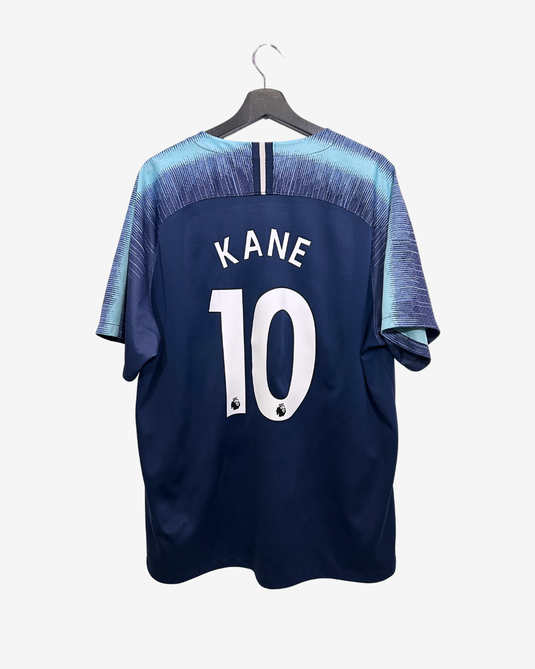 Navy blue sports jersey with 'Kane' and number '10' on a hanger against a white background