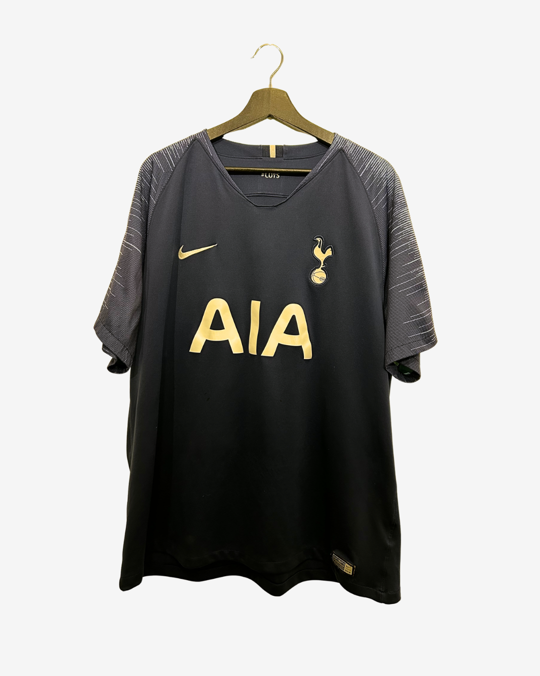 Black sports jersey with gold text and logos on a hanger against a white background