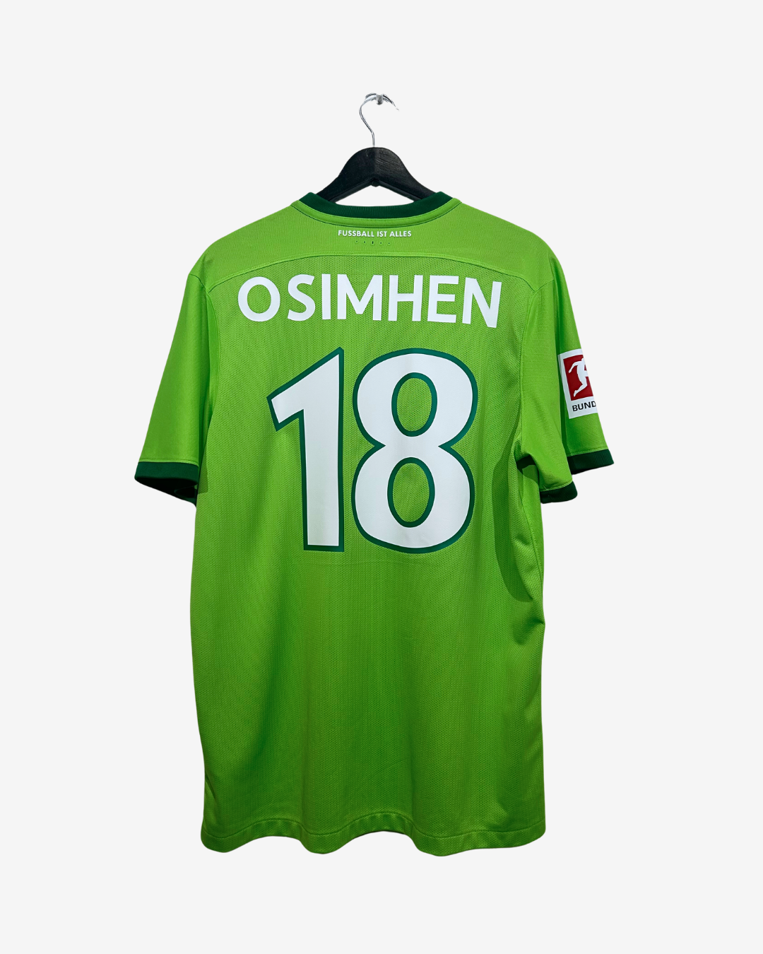A bright green soccer jersey hanging on a black hanger against a light gray background. The back of the jersey features the name 'OSIMHEN' and the number '18' in white with a dark outline.