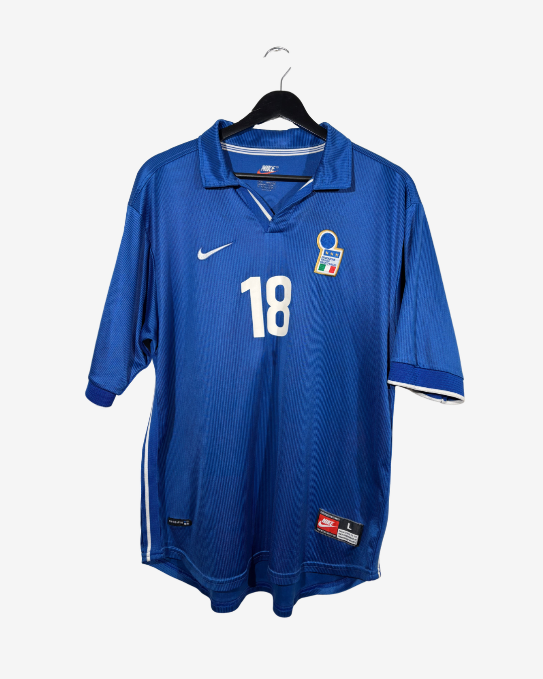 A blue vintage Nike soccer jersey with the number 18 on the front, hanging on a black hanger against a light gray background.