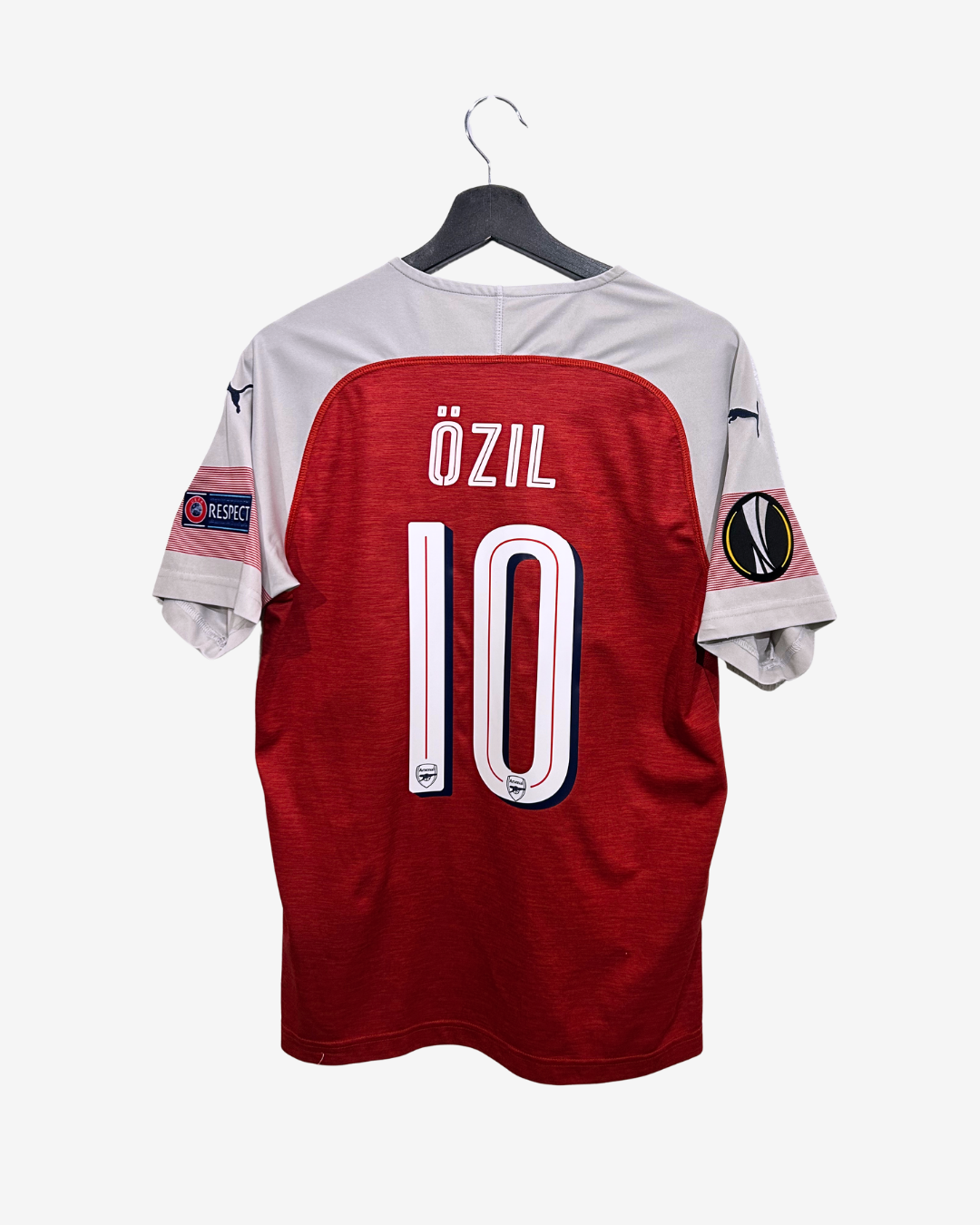 Red sports jersey with 'Ozil' and number '10' on a hanger against a white background