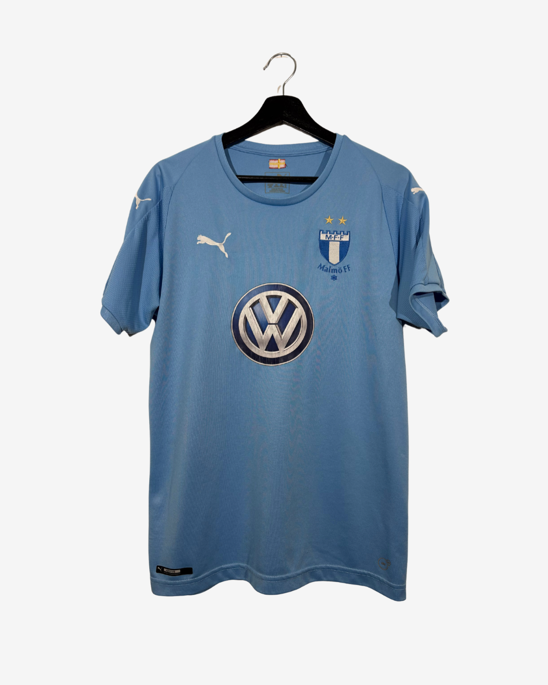 A light blue Puma soccer jersey for Malmö FF, featuring the Volkswagen logo on the front, hanging on a black hanger against a light gray background.