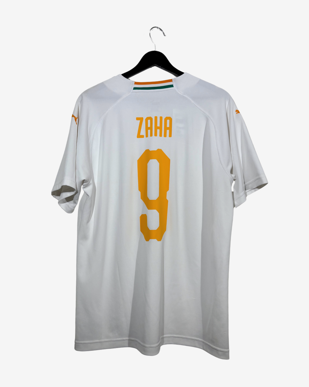 A white short-sleeve soccer jersey hanging on a black hanger against a light gray background. The back of the jersey features the name 'ZAHA' and the number '9' in yellow.