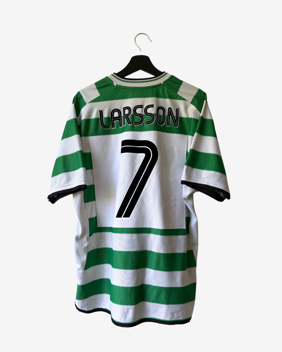 A green and white striped football jersey with 'LARSSON' and the number '7' printed on the back, hanging on a black hanger against a light gray background.