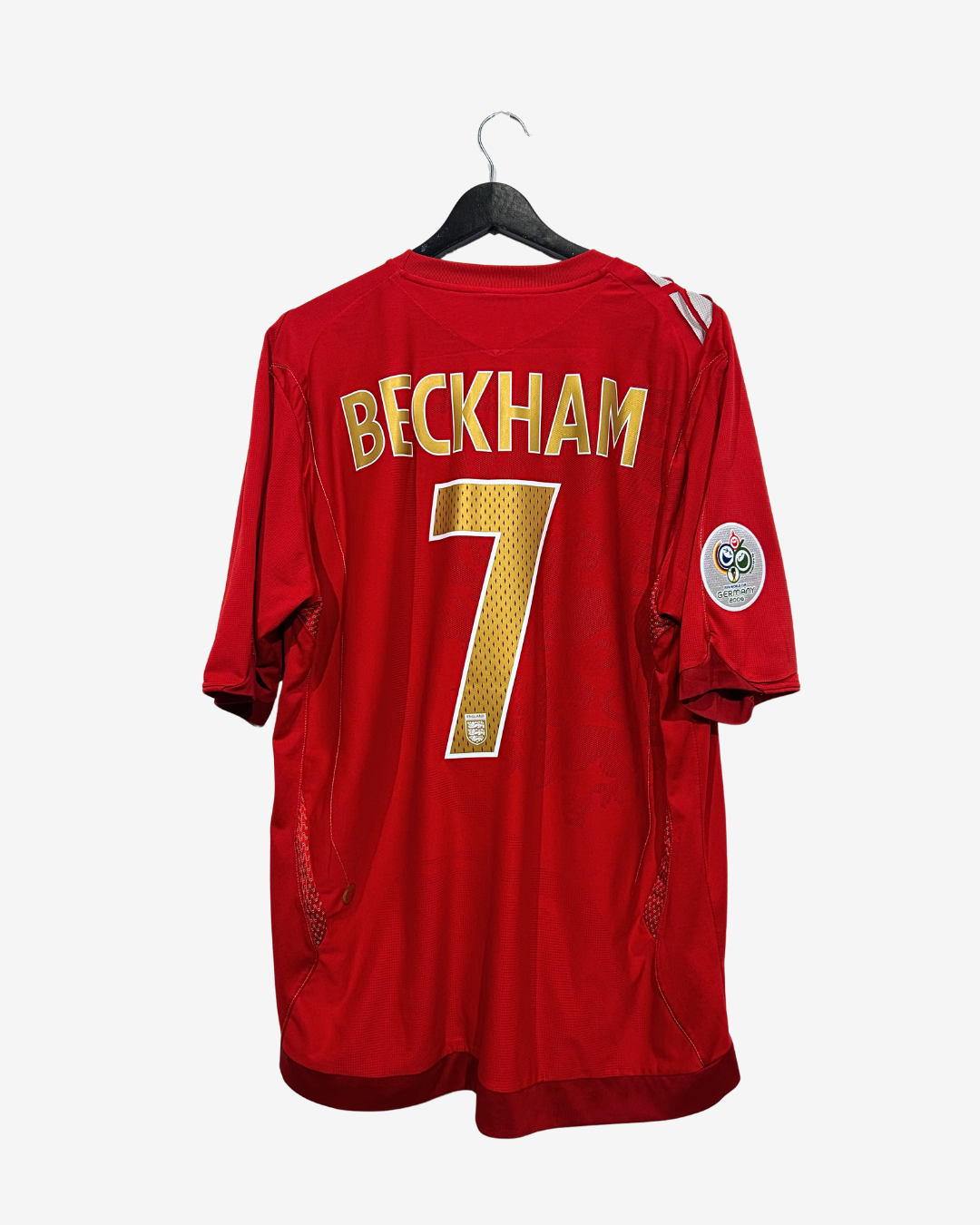 A red Beckham soccer jersey with the name and number 7 in gold on the back, hanging on a black hanger against a light gray background.