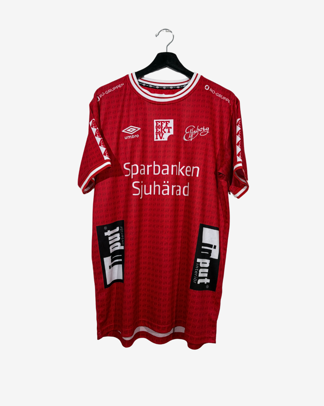 A red vintage football jersey with white and black sponsor logos, hanging on a black hanger against a light gray background.