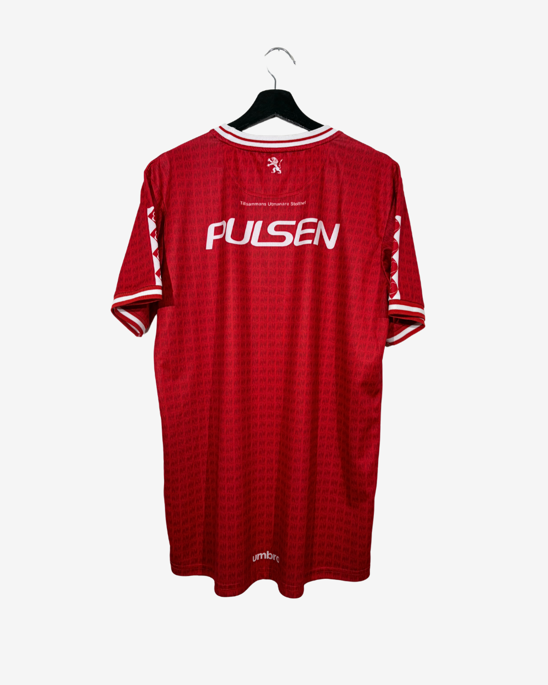 A red short-sleeve soccer jersey hanging on a black hanger against a light gray background. The back of the shirt features the name 'PULSEN' in white across the center, with a small white crest above it and white trim on the collar and sleeve cuffs.