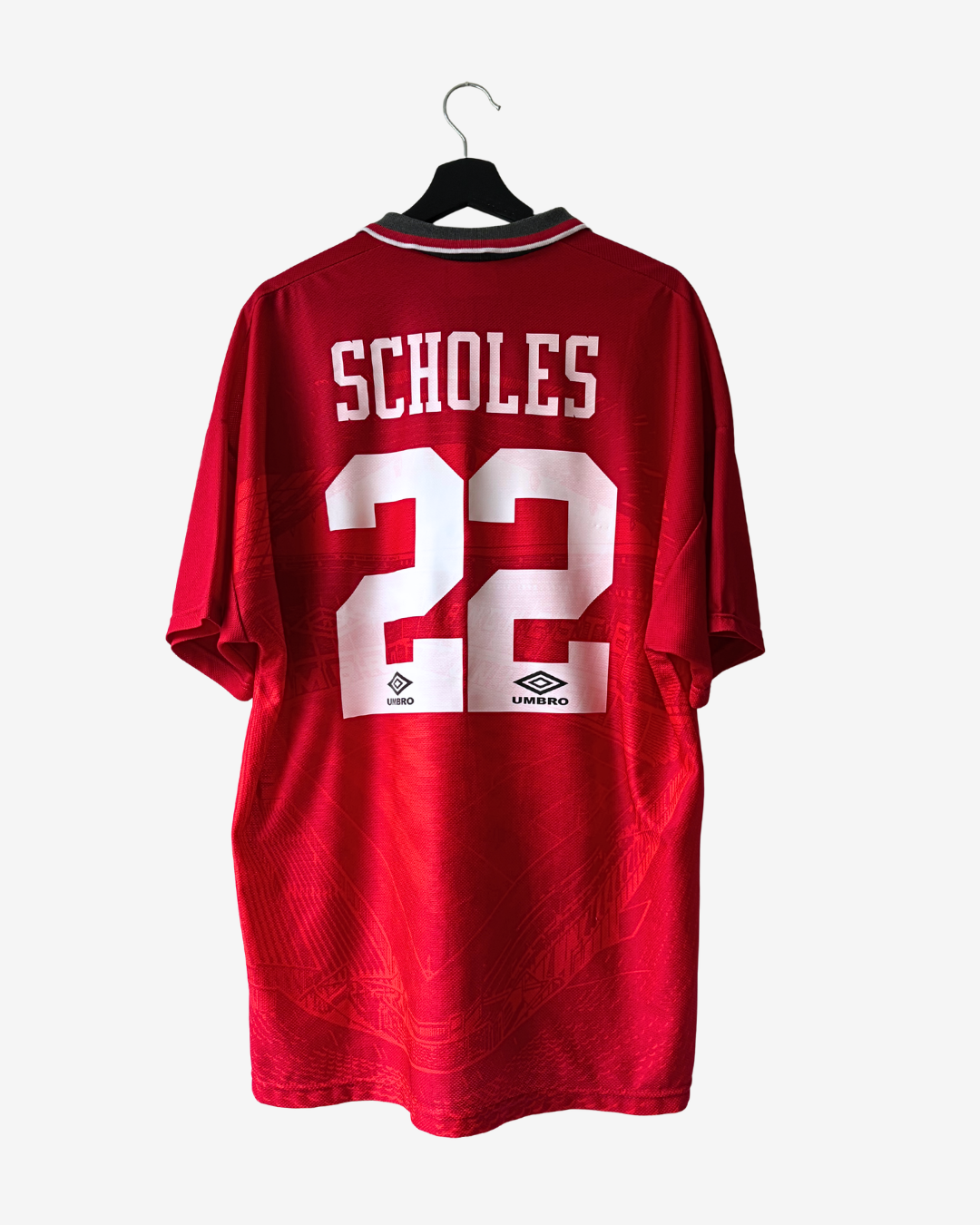 A red short-sleeve soccer jersey hanging on a black hanger against a light gray background. The back of the jersey features the name 'SCHOLES' in white block letters above the number '22' in white, with small Umbro logos beneath the number.