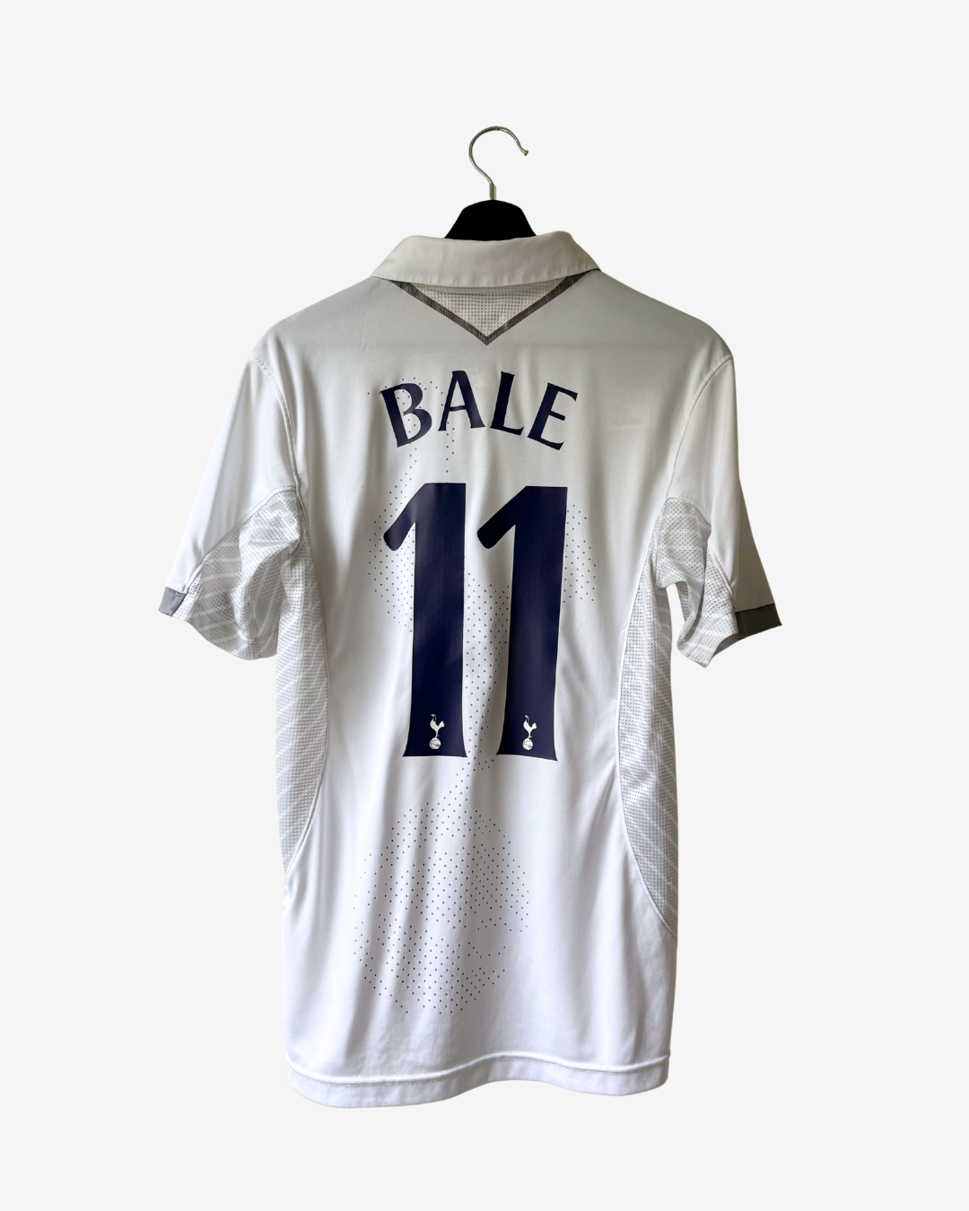 White Tottenham Hotspur football jersey shown from the back on a black hanger, featuring 'BALE' and the number '11' in navy blue.