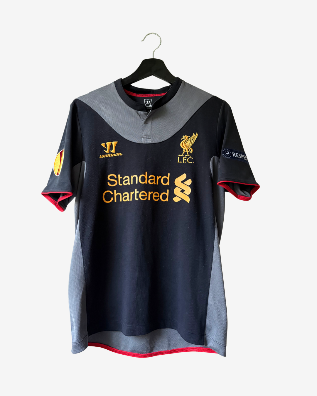 A black and gray Liverpool FC soccer jersey with gold logos, hanging on a black hanger against a light gray background.