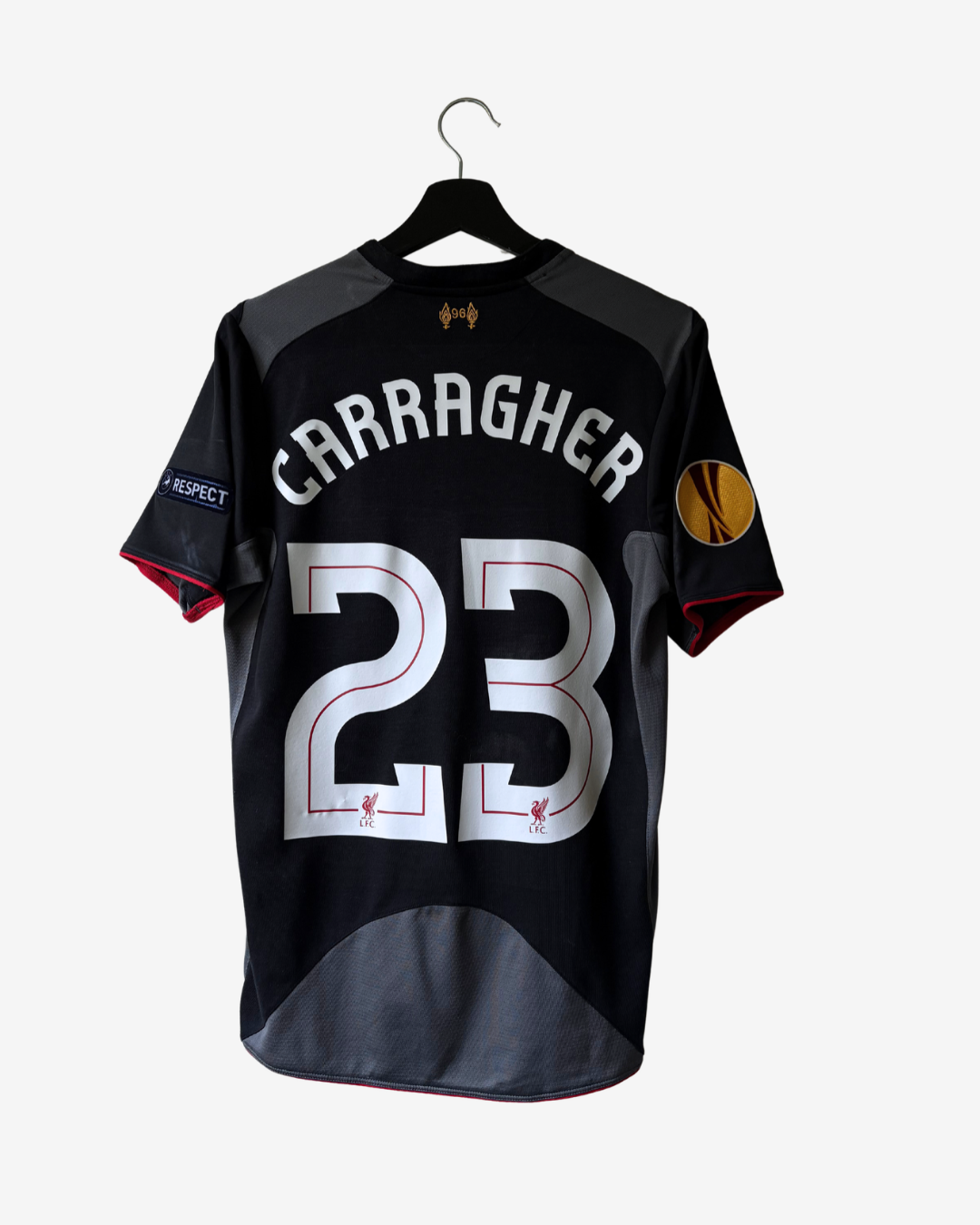 A black Liverpool football jersey with 'CARRAGHER' and the number '23' on the back, hanging on a black hanger against a light gray background.